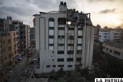 Palestinos buscan sobrevivientes bajo los escombros de un edificio residencial con el tejado destruido por un misil israelí /AP Foto/Khalil Hamra