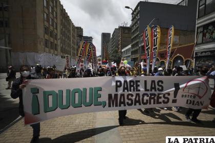 Manifestantes sostienen una pancarta con un mensaje dirigido al presidente de Colombia, Iván Duque /(AP Foto/Fernando Vergara)