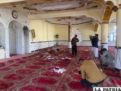 Periodistas afganos toman fotos y videos dentro de una mezquita donde explotó una bomba /AP Foto/Rahmat Gul