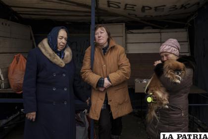 Tres personas que huyeron de la aldea de Ruska Lozova esperan en un puesto de control en Járkiv 
/AP Foto /Felipe Dana