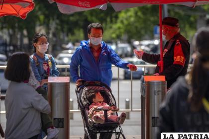 Un guardia de seguridad toma la temperatura de visitantes que entran a un parque público en Beijing /AP Foto/Mark Schiefelbein