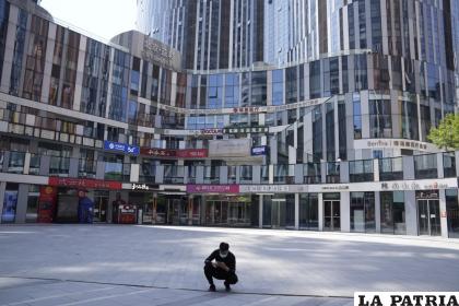 Un hombre con una mascarilla frente a un centro comercial vacío /AP Foto/Ng Han Guan