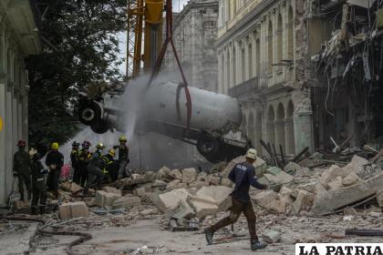 Los bomberos rocían con agua un camión cisterna para enfriarlo mientras lo retiran del lugar de la explosión letal que dañó el hotel Saratoga /AP Foto /Ramón Espinosa