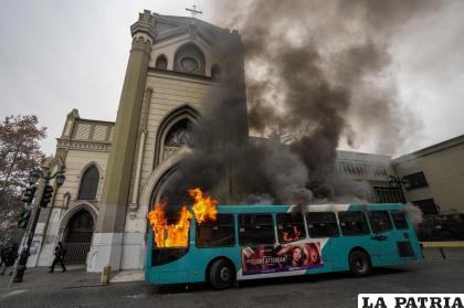 Un autobús está en llamas frente a una iglesia durante una protesta estudiantil en Santiago de Chile / AP Foto/Esteban Felix