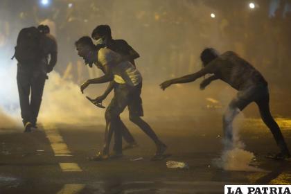Manifestantes anti-gobierno corren para escapar del gas lacrimógeno usado por la policía /AP Foto /Eranga Jayawardena