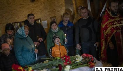 Mykhayl Shulha, centro, llora junto al ataúd de su hermana Sofia Shulha durante un funeral en Uman /AP