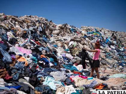 Una mujer busca ropa usada entre toneladas de prendas abandonadas en el desierto de Atacama /Martin Bernetti â€“ AFP
