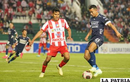 Roberto Fernández con el balón ante la marca de Sebastián Ibarra /APG