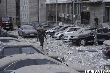 Un agente de policía camina por un estacionamiento con autos dañados, frente a un edificio de varias plantas, luego de un ataque ruso sobre Kiev /AP Foto/Roman Hrytsyna