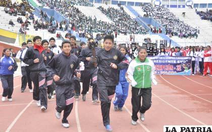 Estudiantes portan la antorcha olímpica ayer durante la inauguración de los juegos