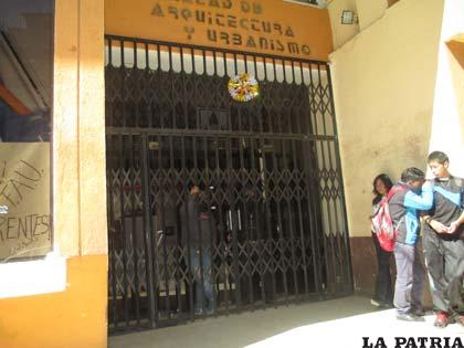 Estudiantes tras las puertas cerradas de la Facultad de Arquitectura