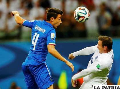 Matteo Darmian de la selección italiana, rechaza de cabeza ante la marca de Rooney