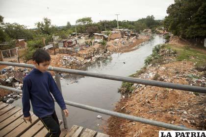 Un niño cruza un puente peatonal, en un barrio pobre de Asunción (Paraguay)