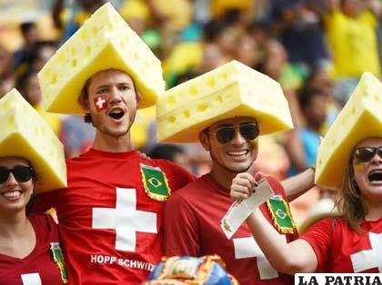Hinchas suizos festejan el triunfo de su selección con sombreros de queso