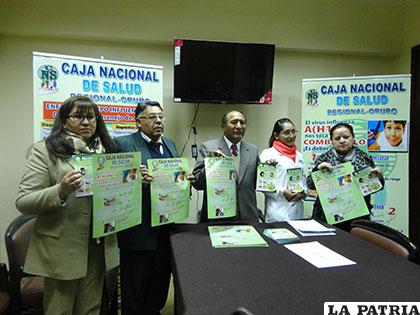 Autoridades de la Caja Nacional de Salud mostrando los afiches sobre la influenza
