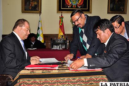 El ministro de Gobierno, Carlos Romero (izq.) y el alcalde de Sabaya, Egdón Villca (der.), firman el documento