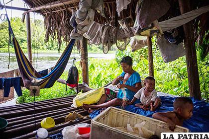 Fotografía fechada el 10 de mayo de 2018, que muestra a una mujer de la etnia Warao junto a sus hijos, en su palafito (vivienda Warao) en la ribera del río Morichal, en Maturín
