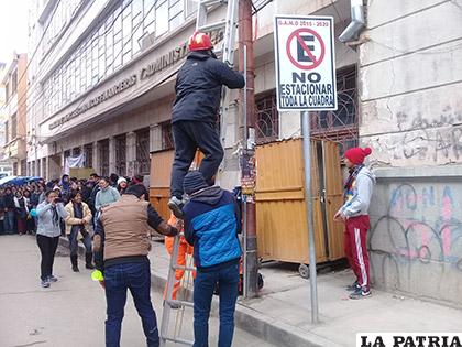 Dos estudiantes sujetan la escalera para que suba el voluntario del SAR Bolivia