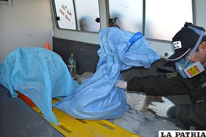 Un funcionario de Homicidios acomoda en sacos los restos de la fallecida /LA PATRIA