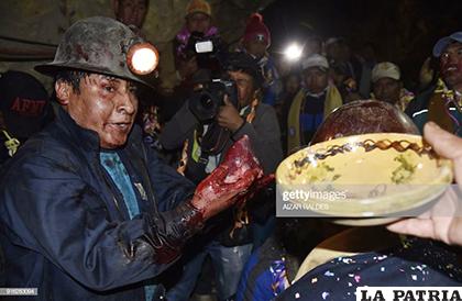 Un minero sostiene el corazón de una llama luego de regar el socavón con la sangre del animal