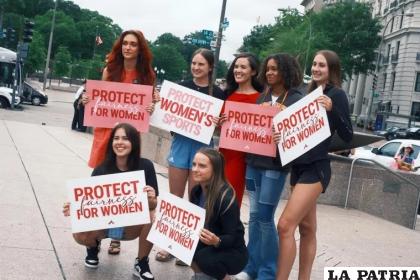 Un grupo de mujeres sostiene pancartas que dicen “Protege la equidad para mujeres” y “Protege el deporte femenino” /EFE
