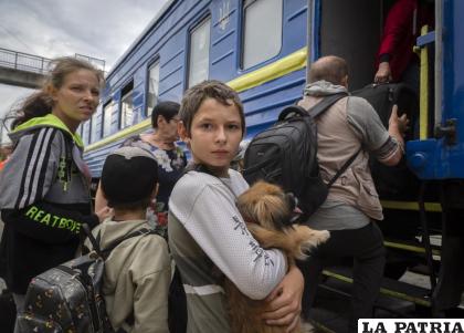 Un niño sostiene a su perro mientras su familia abandona una zona afectada por la guerra /AP Foto /Efrem Lukatsky