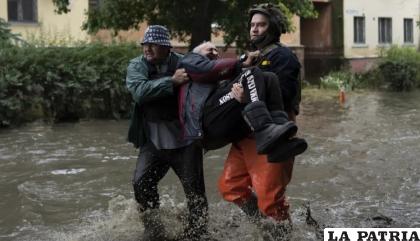 Dos rescatistas ayudan el domingo 11 de junio de 2011 a trasladar a zona segura a un hombre que fue atacado por las fuerzas rusas /AP