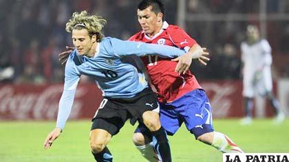 Forlán y Medel disputan la pelota