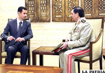 El presidente de Siria, Bashar al Asad (i), conversa con el general Fahd Yasem al Freich, nuevo ministro de Defensa, tras jurar este último su cargo. Foto: EFE