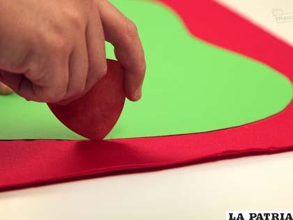 PASO 1
Ahora toma el molde de cartulina con forma de manzana que habías hecho y dibuja su contorno sobre la tela roja usando la tiza.