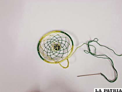 PASO 5
Conforme vas tejiendo la red, puedes ir introduciendo pequeñas cuentas entre los hilos.
Cuando termines la red, no cortes el hilo y cose una piedra en el centro.
La mía era un hueso de cereza pintado. 
Después puedes hacerle una presilla para colgarlo o simplemente un trocito de hilo.