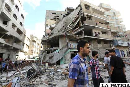 Hombres observan los daños materiales en un edificio destruido durante un atáque aéreo del ejército israelí en Gaza