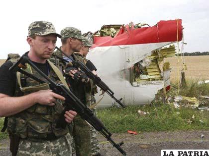 Rebeldes prorrusos armados permanecen apostados al lado de los restos del fuselaje del avión Boeing 777
