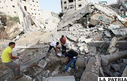 Un grupo de palestinos rescatan restos de personas de escombros provocados por bombardeo israelí en Gaza