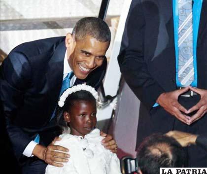 Barack Obama posa con una niña tras ser recibido por el presidente de Kenia