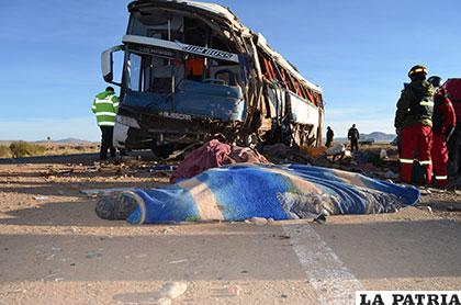 Los cuerpos de los dos fallecidos yacen delante del bus volcado
