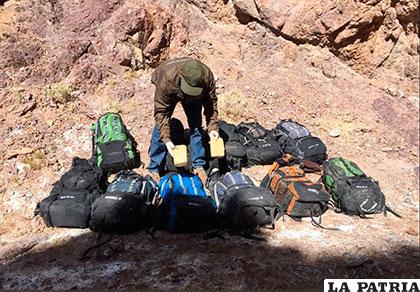Uno de los carabineros verificó el contenido de las mochilas con droga encontradas a los bolivianos /Carabineros Chile