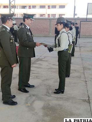 Una funcionaria policial recibe un reconocimiento de manos del comandante departamental, coronel Rommel Raña