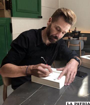 El escritor Rodrigo Costoya Santos firma un ejemplar de su novela en español /EFE