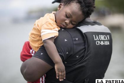 Un migrante haitiano sostiene a su hijo antes de abordar un bote hacia Capurgana cerca de la frontera con Panamá / AP Foto/Ivan Valencia