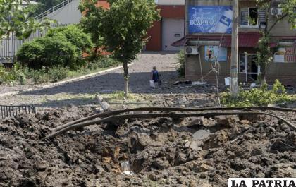 Una mujer camina al lado de un enorme cráter causado por un ataque ruso con misiles /AP Foto /Efrem Lukatsky