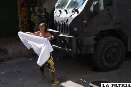 Una residente agita una sábana blanca para pedir paz después de una operación policial /AP Foto/Silvia Izquierdo
