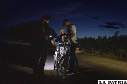Un agente de policía ucraniano comprueba la documentación de un hombre y una mujer que circulan en bicicleta, durante el toque de queda nocturno /AP Foto /Nariman El-Mofty
