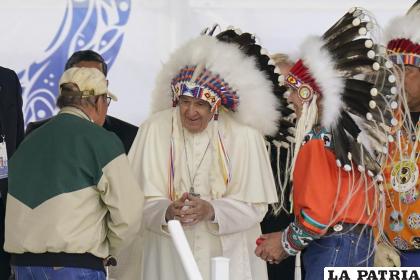 El papa Francisco dialoga mientras viste un penacho durante una visita a los pueblos indígenas en Maskwaci /Foto AP/Eric Gay
