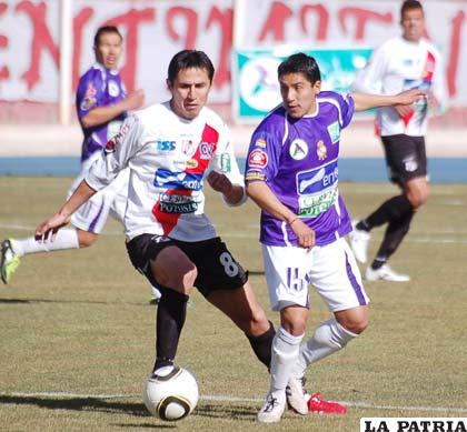 Edgar Escalante (Nacional Potosí) disputa el balón con Ariel Juárez (Real Potosí)