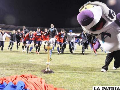 La mascota de la Copa AeroSur junto al trofeo de campeón