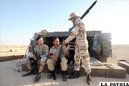 Soldados rebeldes conversan tras una barricada en el enclave petrolero de Ras Lanuf (Libia), cerca a Trípoli