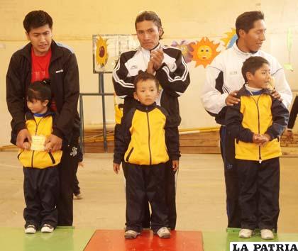 Los ganadores de la prueba junto a sus pequeños hijos en el podio de los ganadores 