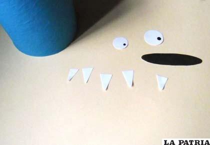 PASO 3
Luego, mira un dibujo de un monstruo y copia la forma de los ojos, la boca, los dientes y recórtalos en papeles de colores.