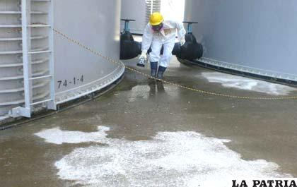 Un empleado mide la radioactividad en la base de un tanque de almacenamiento que contiene agua de un alto nivel de radioactividad